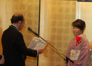大野選考委員長より、賞状を受け取る河村啓子さん（右側）