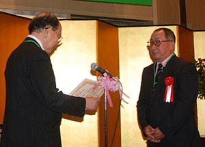 大野選考委員長より、賞状を受け取る黒川利一さん（右側）